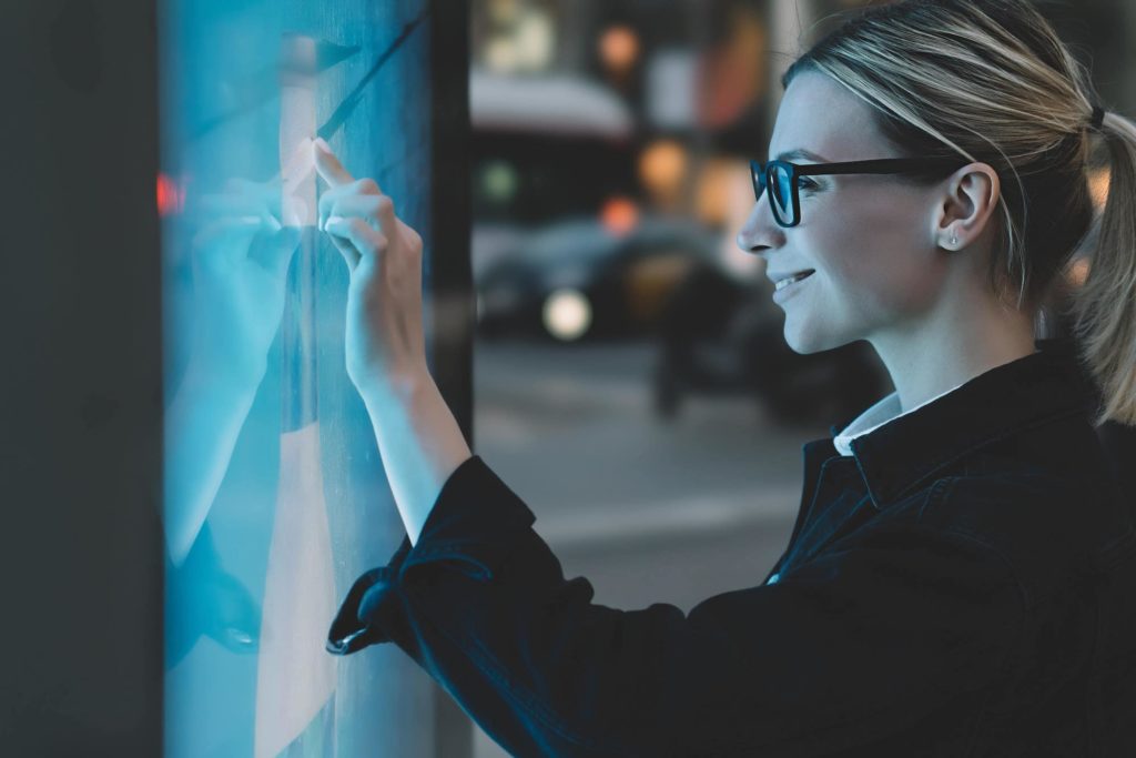 femme avec lunettes touche du doigt un écran tactile