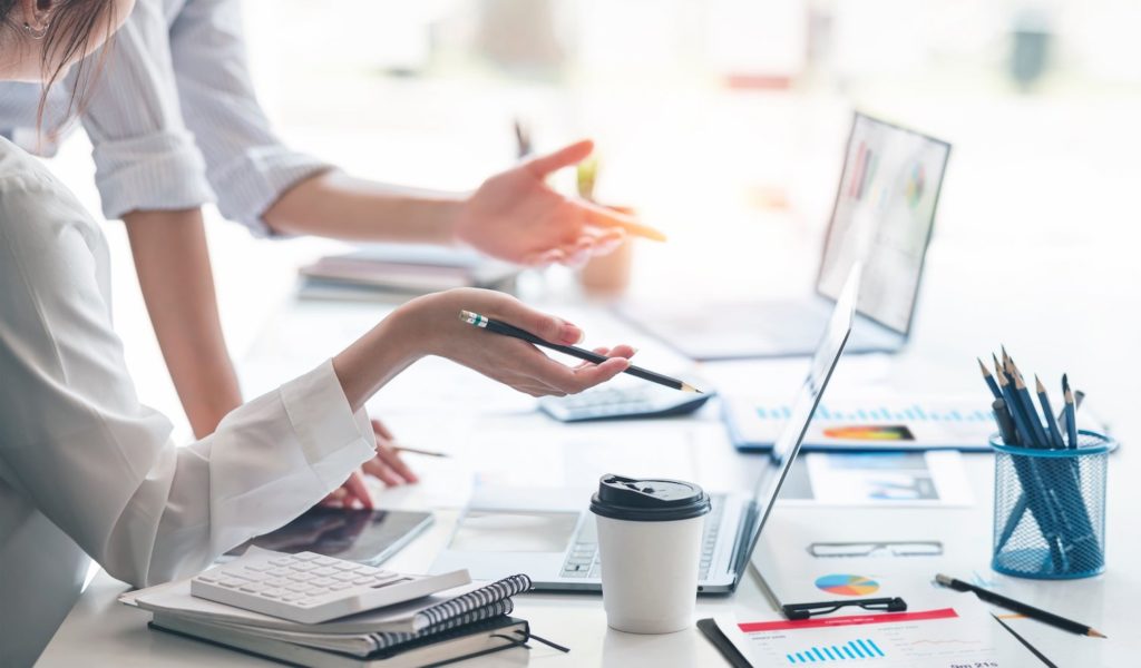2 personnes travaillant sur un bureau avec des ordinateurs portables